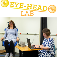 Logo of the Eye-Head Lab above a picture of Natela Shanidze testing a participant