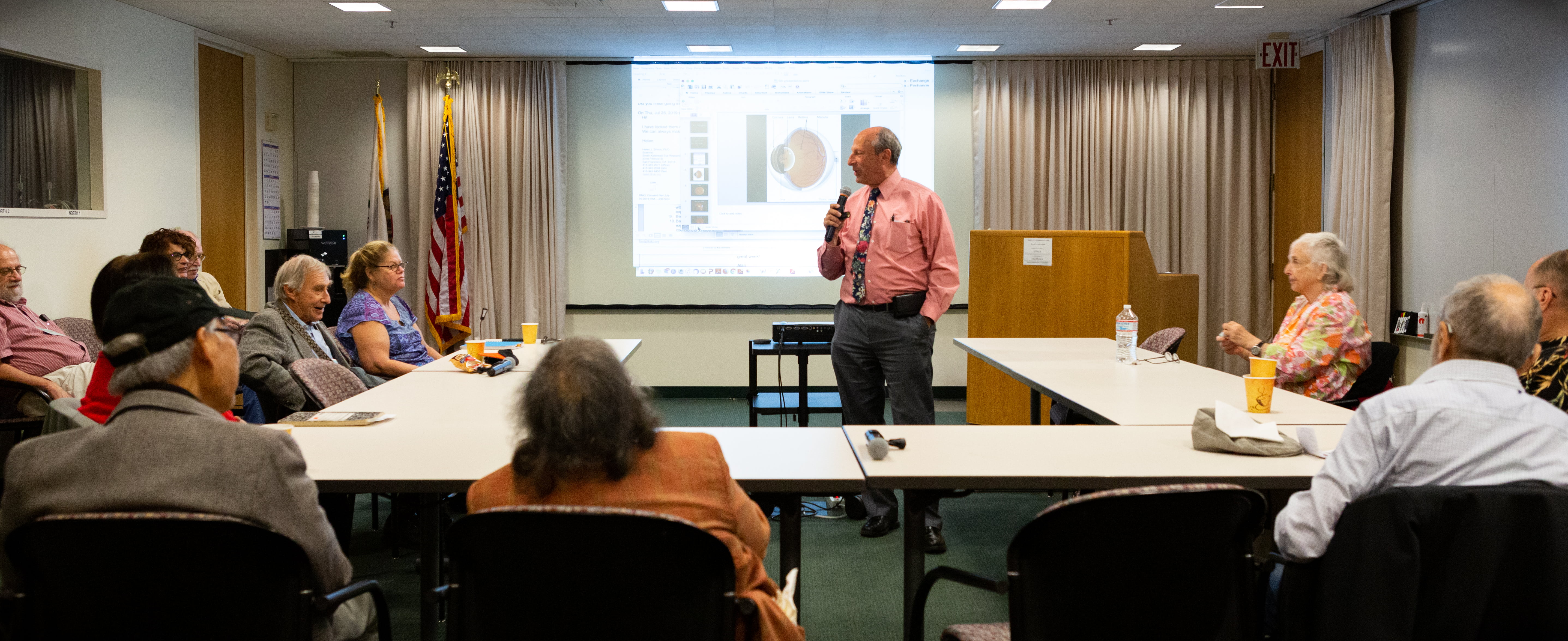 Dr. Fletcher speaking in front of a projection of an eyeball